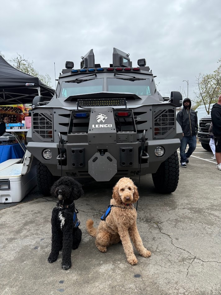 Two service dogs in front of a Lenco vehicle at a law enforcement memorial event