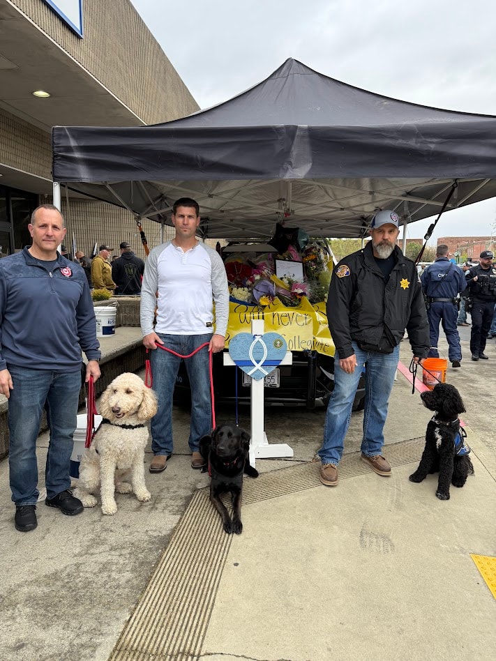 Law enforcement supporters, service dogs, and a memorial display at a remembrance event