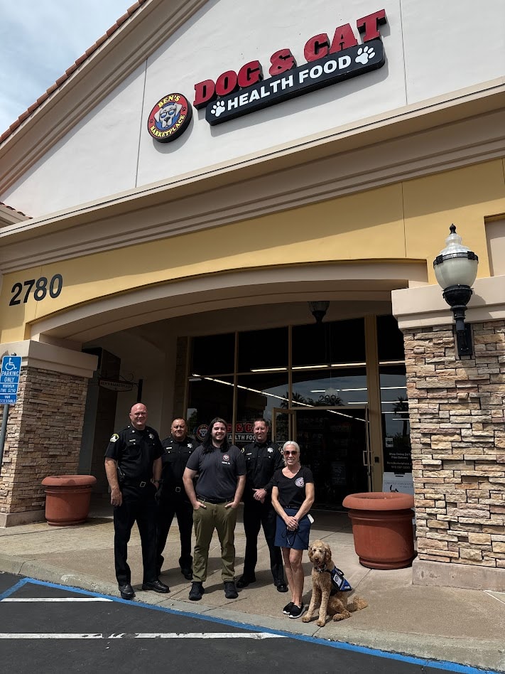 Community members and a therapy dog outside Dog and Cat Health Food
