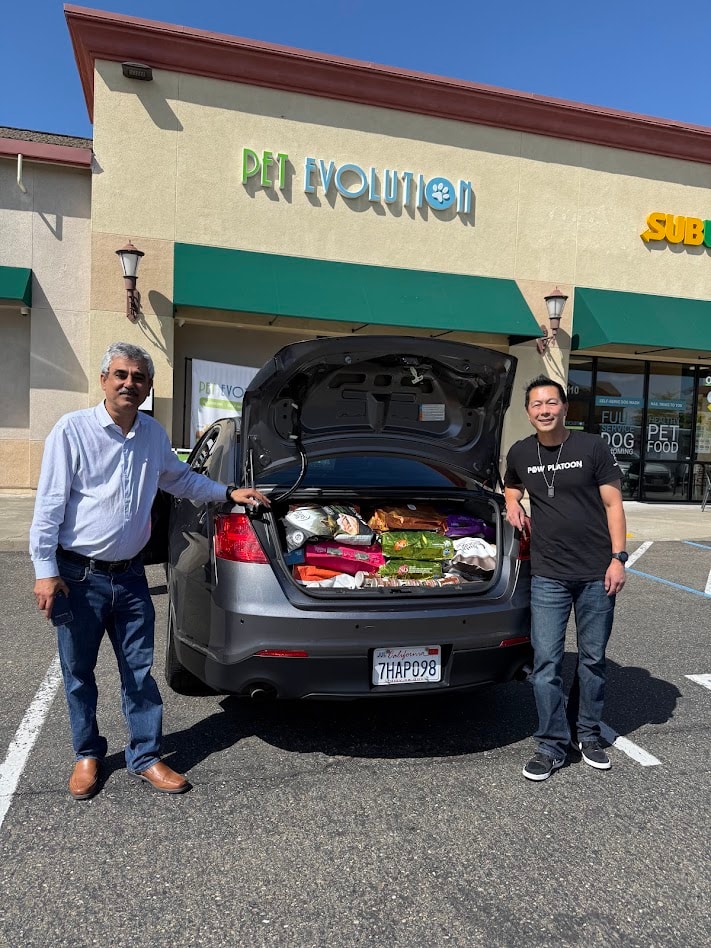 Community members beside a vehicle filled with donated pet food outside Pet Evolution