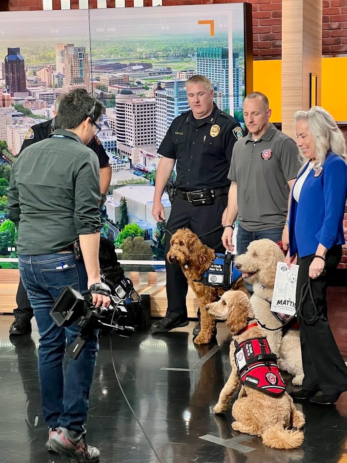 News camera filming Hearts 4 Heroes USA representatives and therapy dogs in the studio